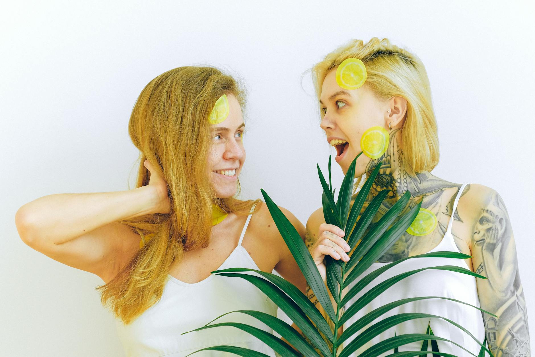 Two women smiling joyfully with lemons, expressing happiness and confidence