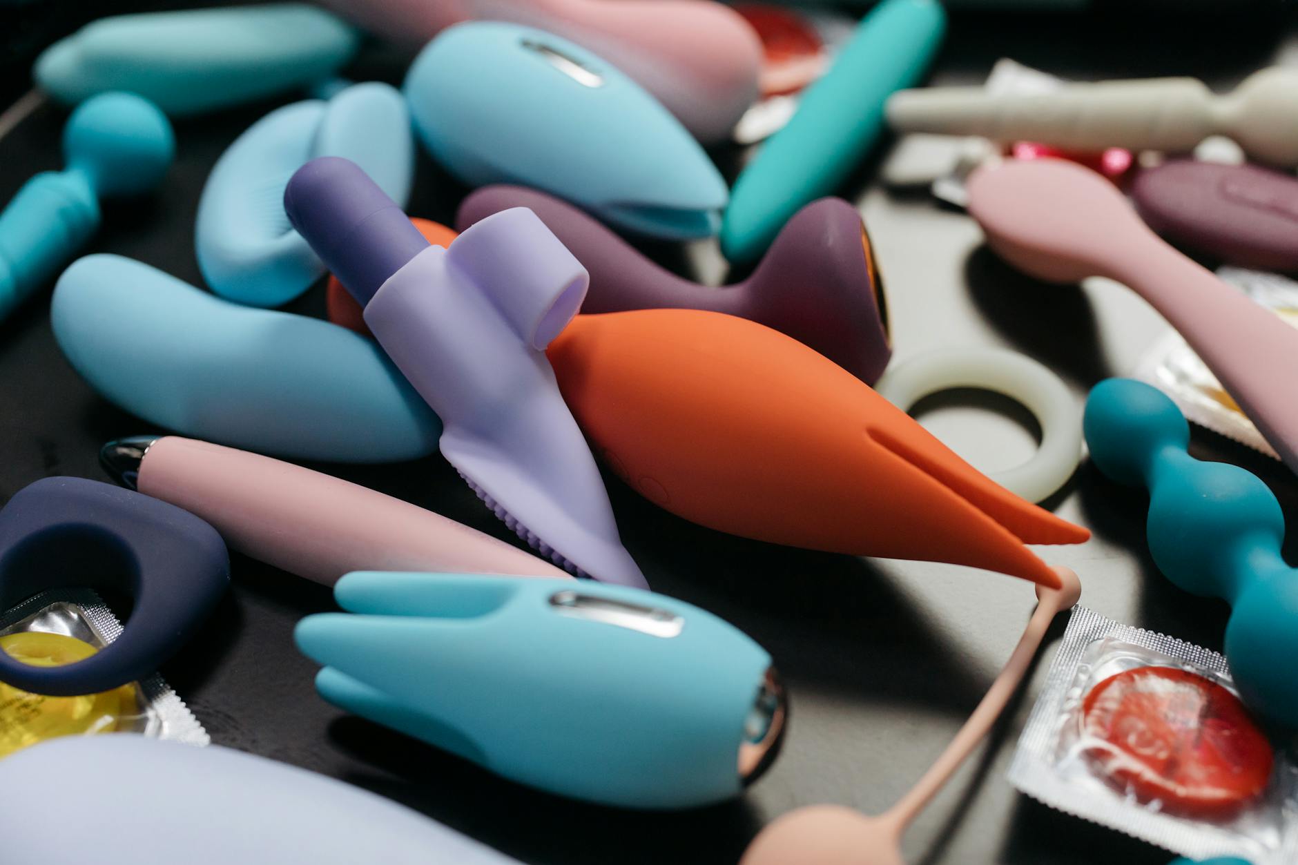 Woman holding blue and pink vibrators in thoughtful pose, representing pleasure recovery.
