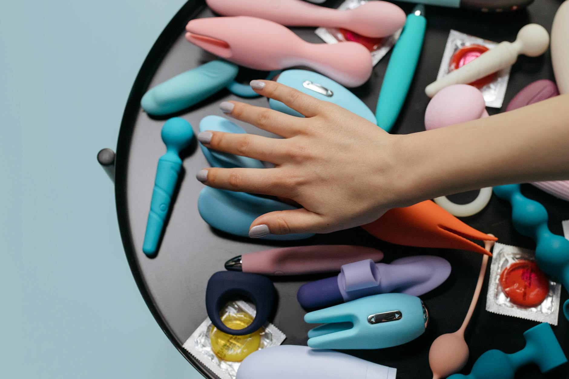 Woman holding blue and pink silicone vibrators while considering pelvic health options