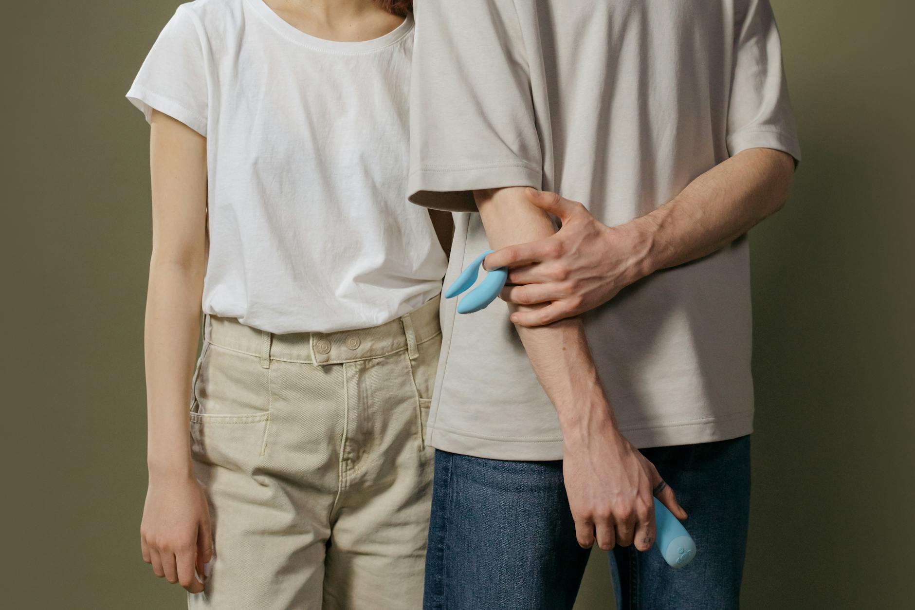 A couple holding a modern vibrator together indoors, representing shared intimacy and toy selection