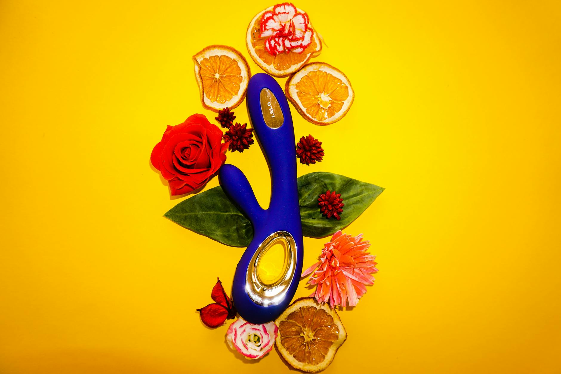 Hand holding an orange vibrator against a purple backdrop, showcasing modern sensuality and pleasure tools