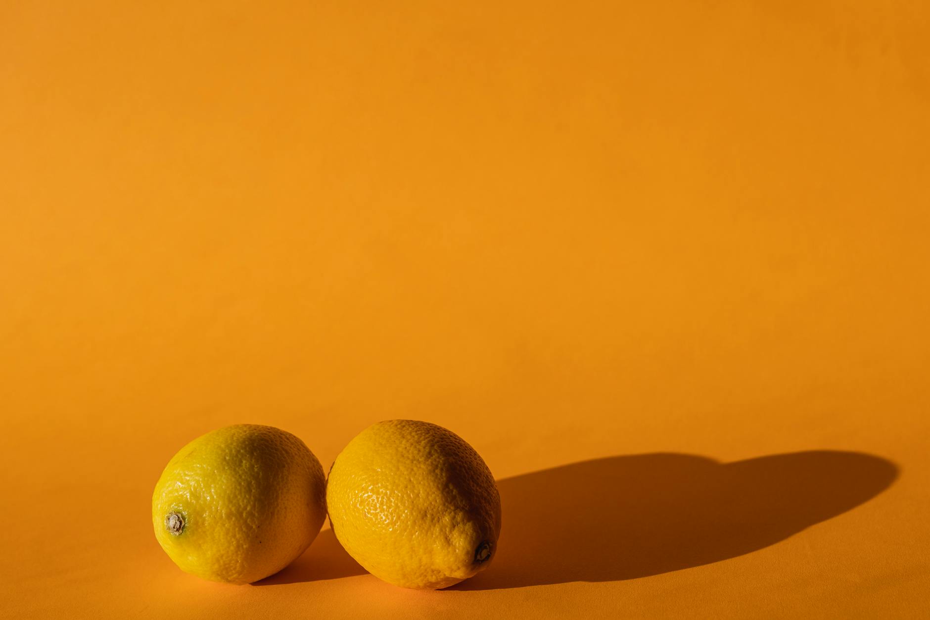 Halved fresh lemons on a pink background in sunlight, symbolizing reconnection and renewal